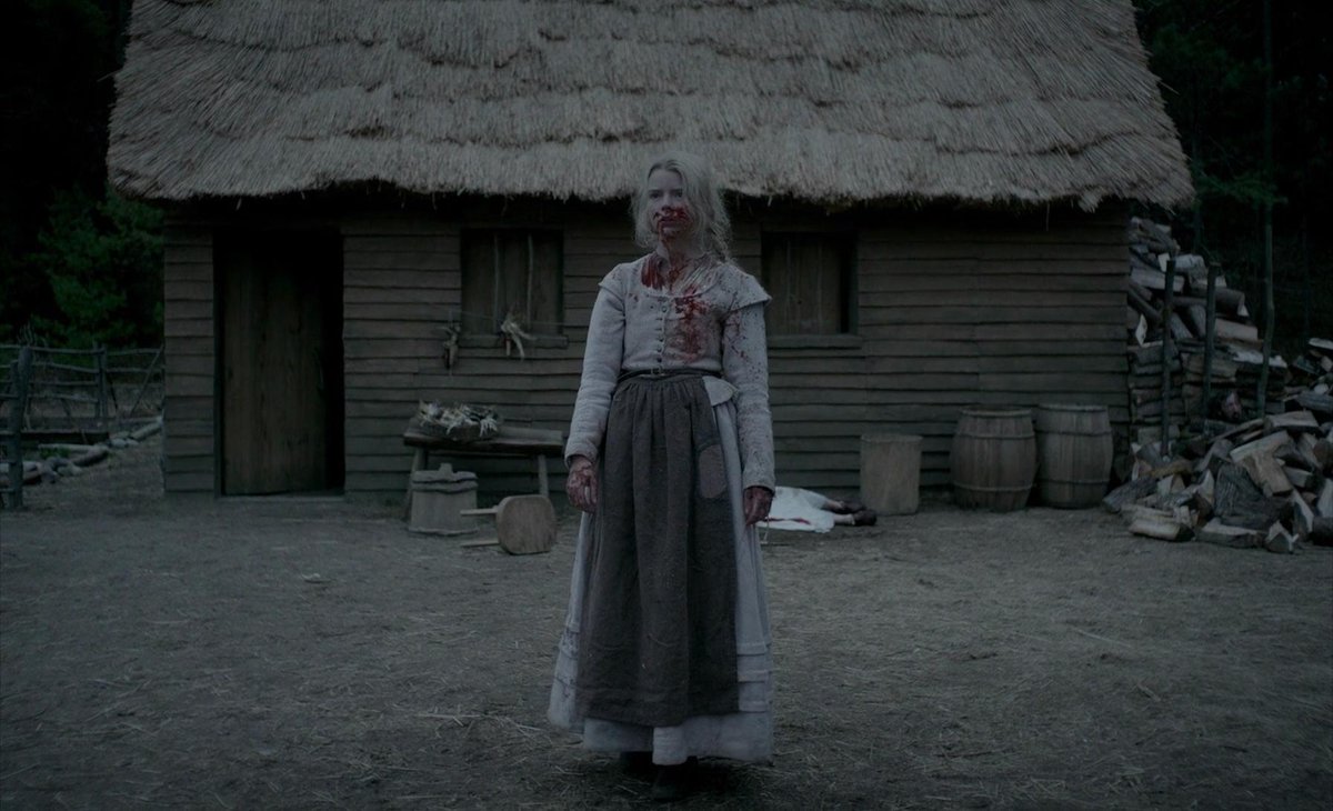 Thomasin stands in front of her shed, covered in blood.