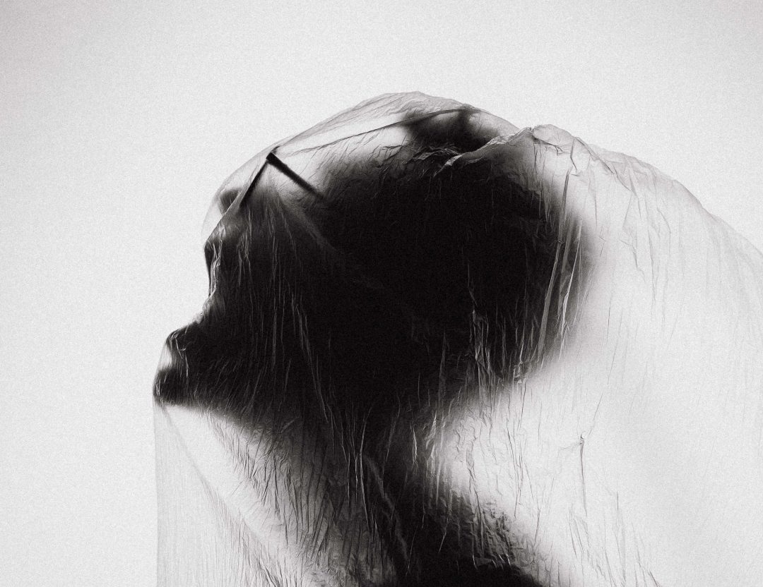 A black and white photo of a person screaming with something draped over their head.