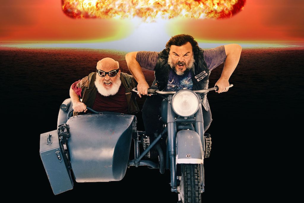 Jack Black and Kyle Gass as Tenacious D, riding a motorcycle away from an explosion. 