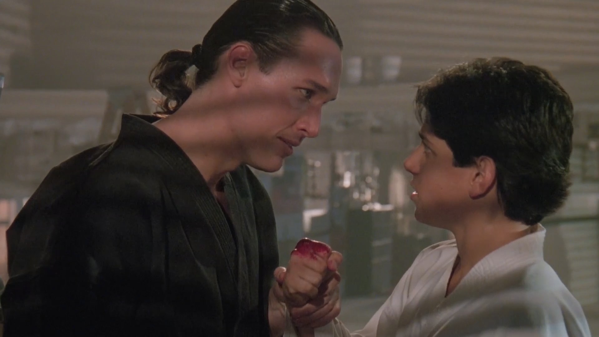 Terry Silver regards a young Daniel LaRusso's bloodied fist after training.