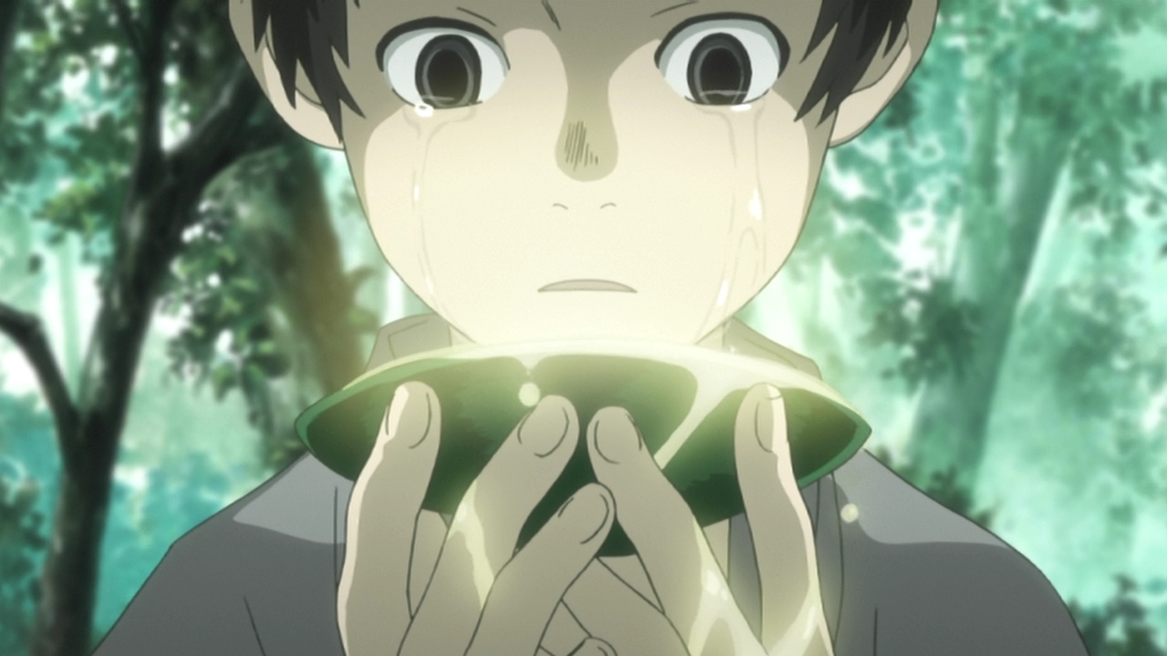 A boy stands holding a green sake cup up to his face while he cries.