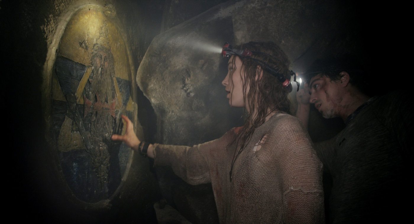 Scarlett and George look at one of the clues within the tunnels they are in in order to find their way out.