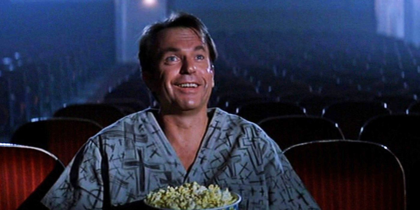 Sam Neill seated in a movie theatre with popcorn.