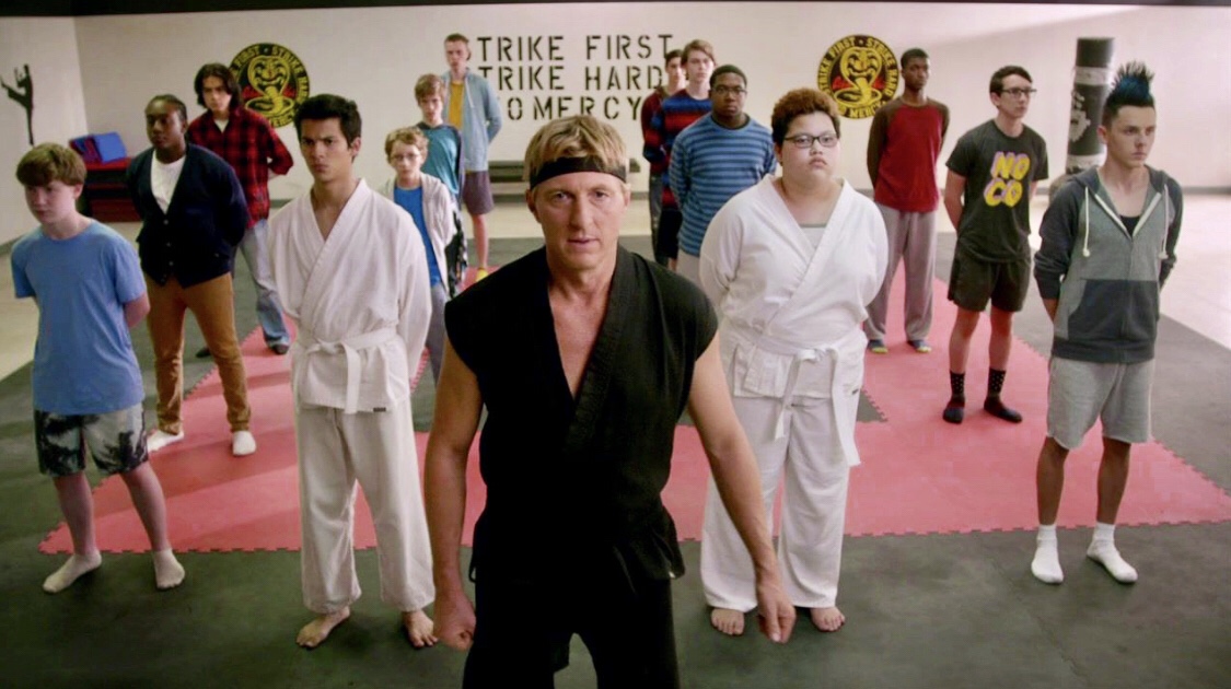 Cobra Kai's Johnny Lawrence stands in front of his karate dojo leading students.