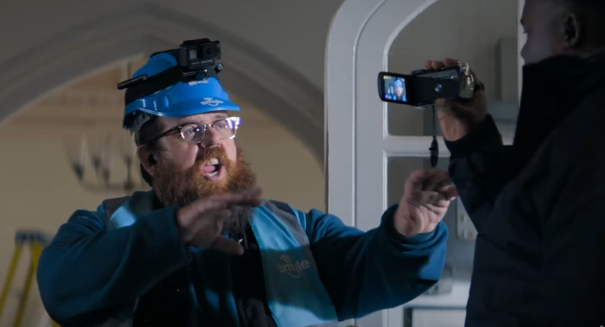 Gus being filmed for his amateur paranormal investigation YouTube channel, "Truth Seekers." He is wearing a blue hard hat with a mounted camera. He is in mid sentence.