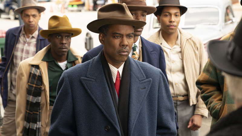 A group of men in suits walk toward the viewer.