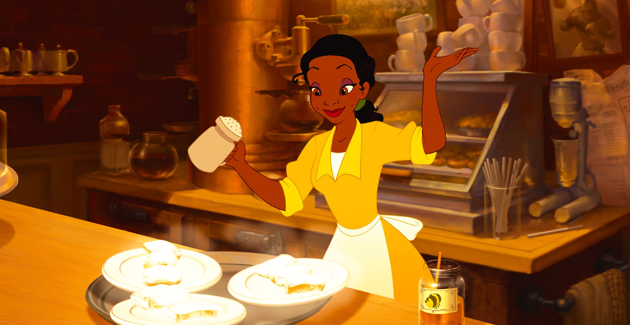 Tiana holds a shaker as she stands in front of a tray of food.