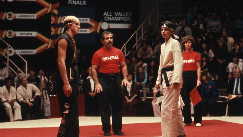 Cobra Kai's Johnny faces Miyagi-Do's Daniel in sparring ring.