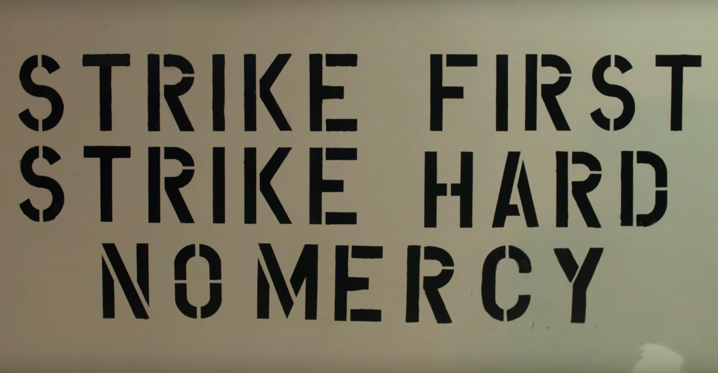 The famous words "strike first strike hard no mercy" painted in black stand out on a white wall at the Cobra Kai dojo.