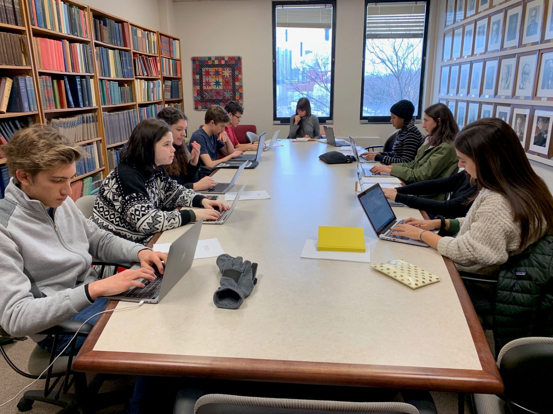 Students at the Iowa Writer's Workshop sit at a long, rectangular table and write independently on laptops.