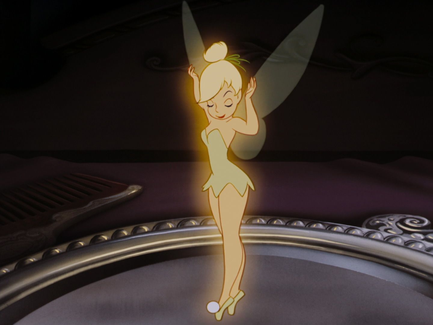 Tinkerbell stands on a plate looking down with her eyes closed.