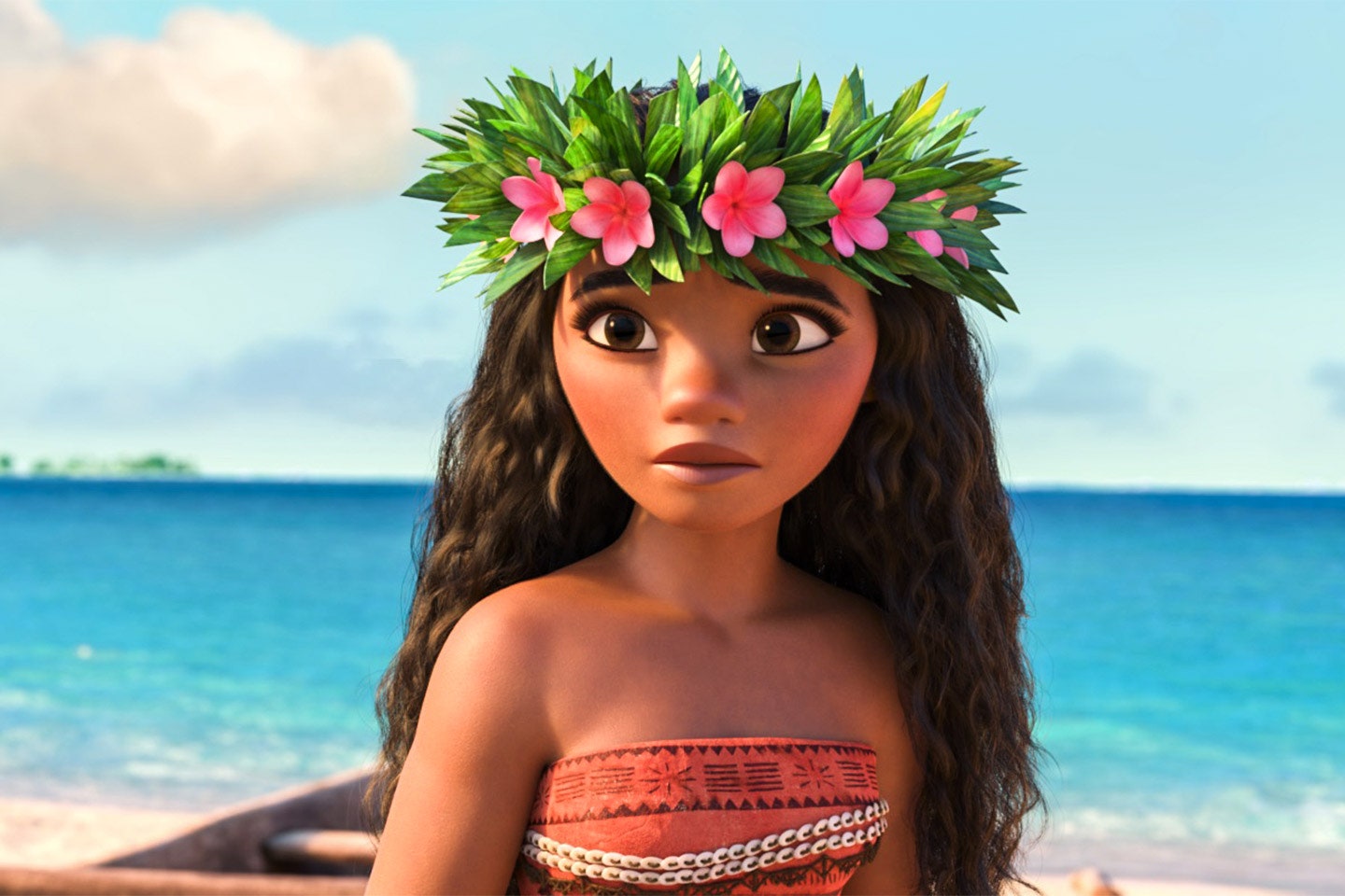 Moana stands in front of the ocean with wearing a wreath of flowers in her hair.