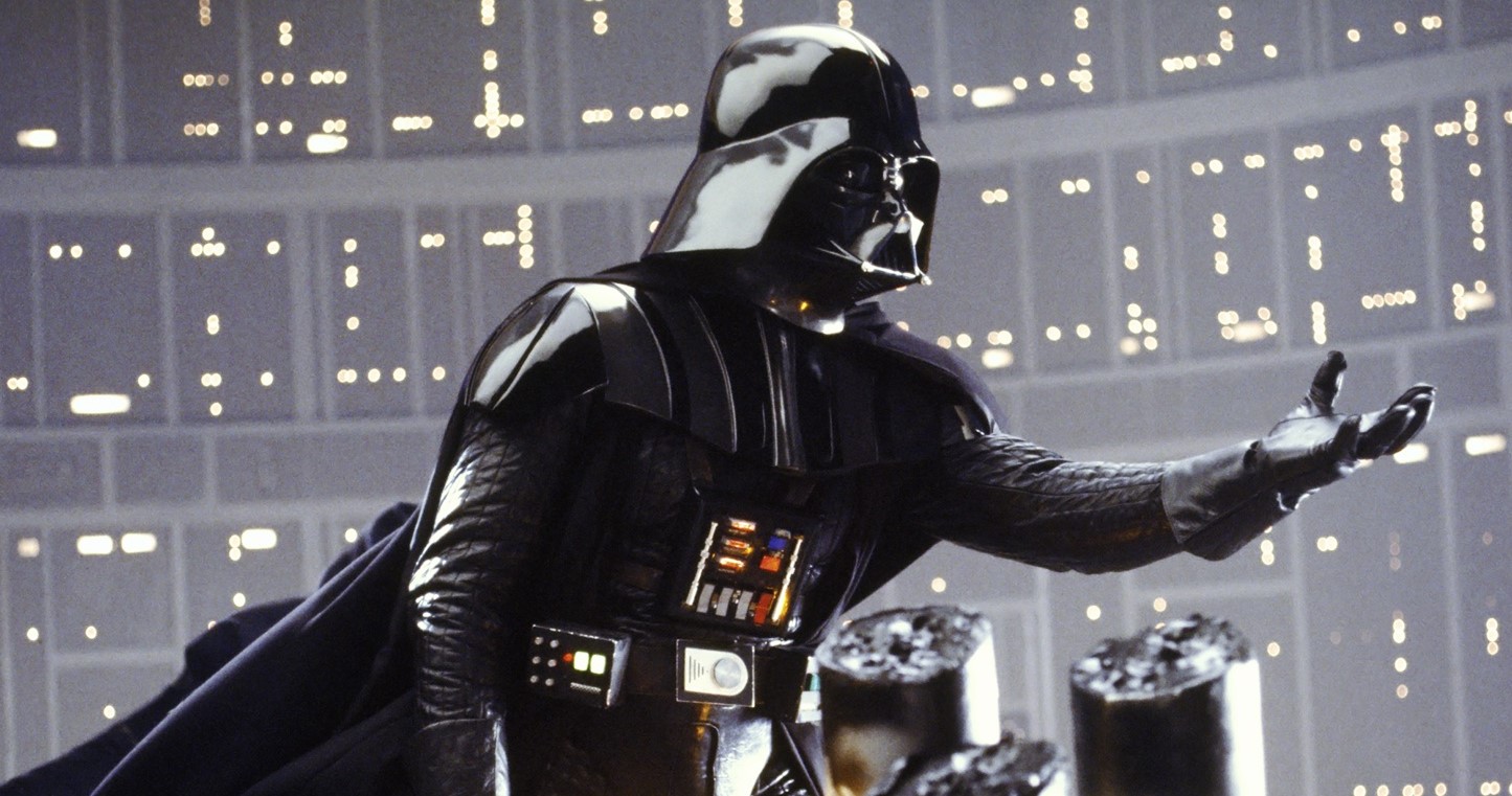 Darth Vader raises a menacing, clawed hand.