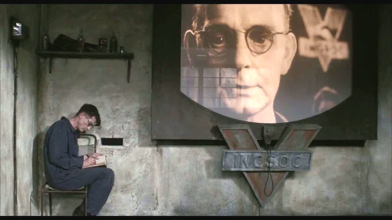 Big Brother looms on a large screen in 1984, while the protagonist hovers in the corner.