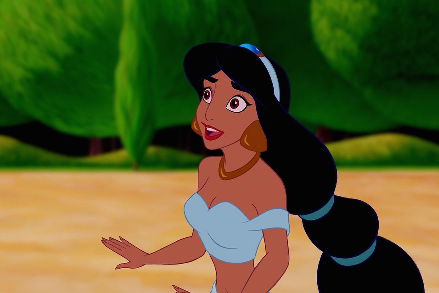 Jasmine stands in front of green trees looking at something off the screen.