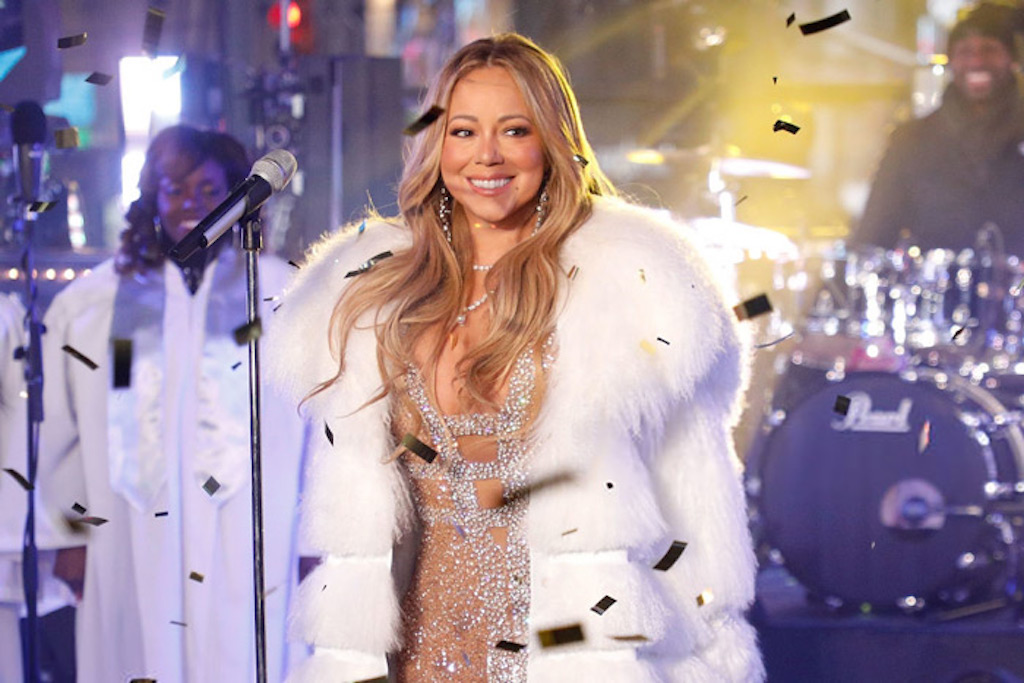 Mariah Carey standing on stage in a fur coat and sparkly dress during her 2017 New Years' Eve performance.