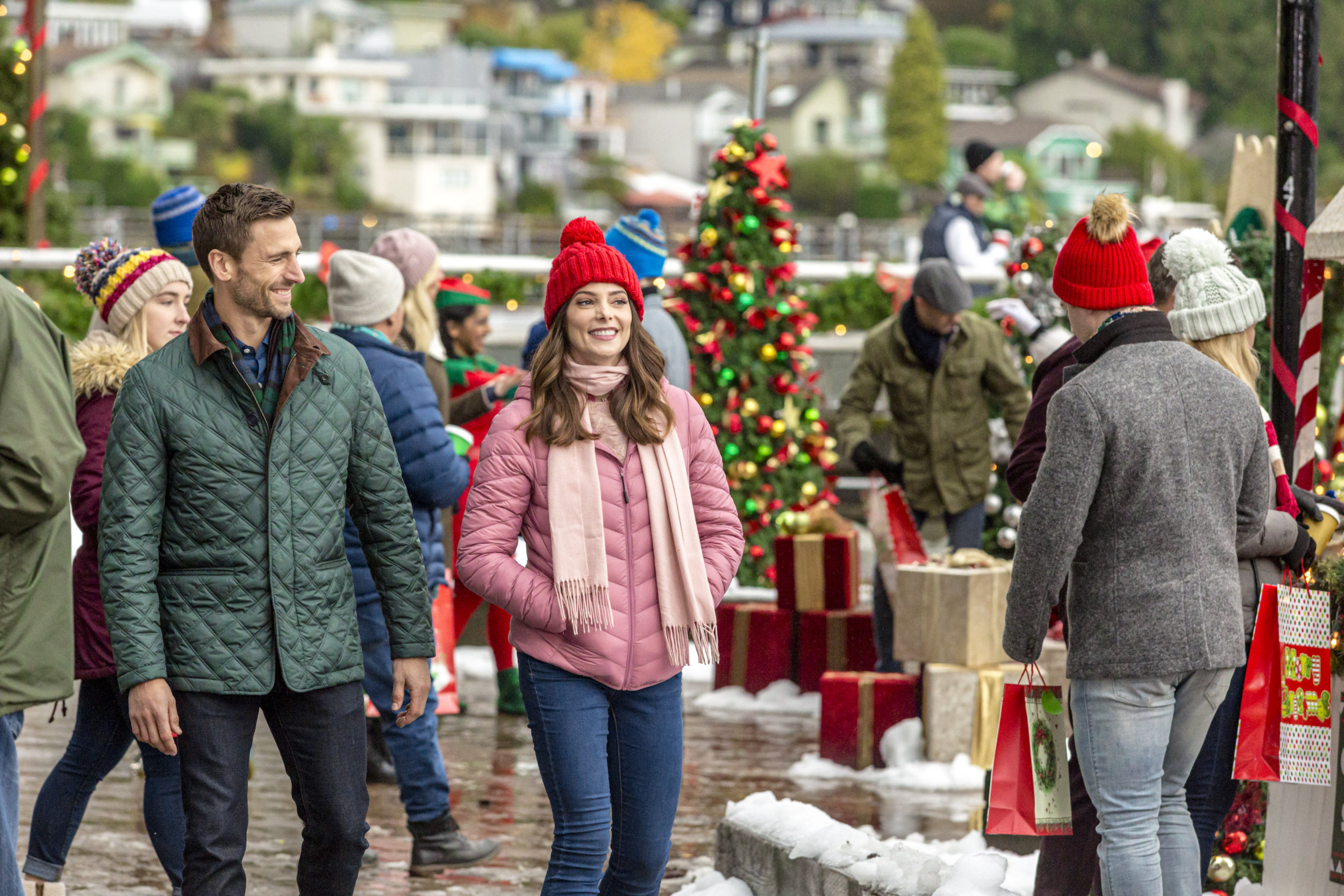 A man and woman walk through an outdoor Christmas market.