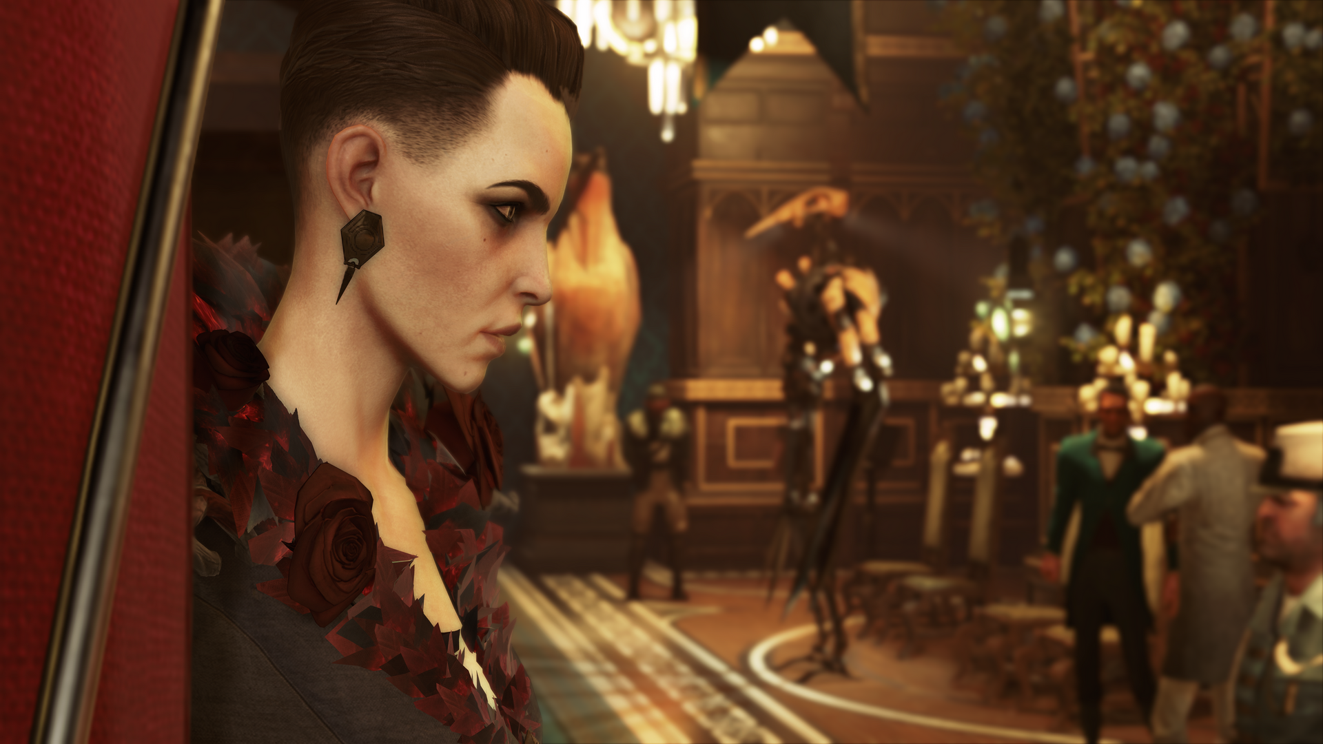 Delilah can be seen in profile. She is a slender white woman with short, dark hair, heavy eyeliner, and sharp features. She wears heavy earrings and a jacket collared with red roses. The background is blurry, with a few indistinct human shapes.