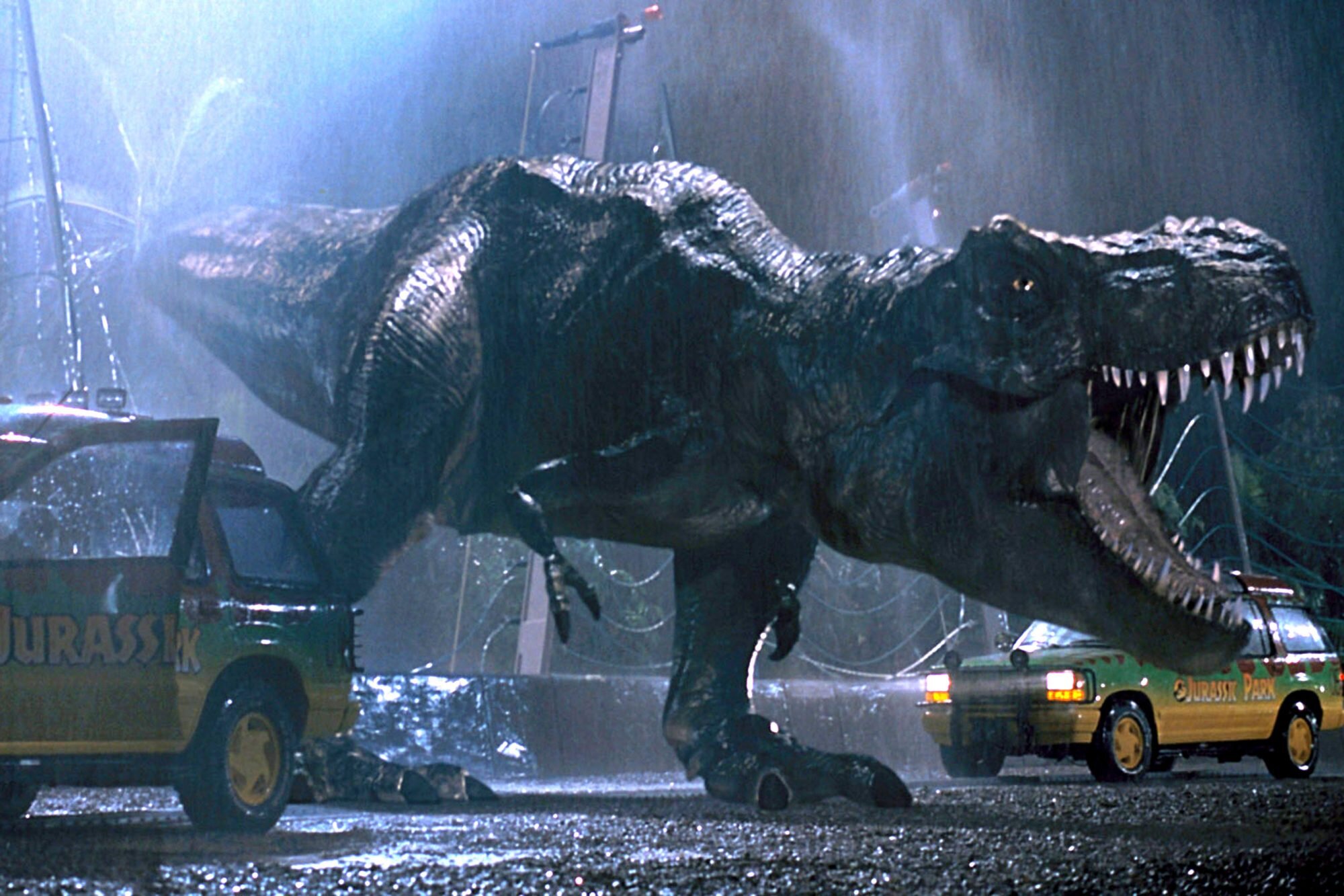 The tyrannosaurus rex after breaking out of his cage and roaring in between the two Jurassic Park cars.