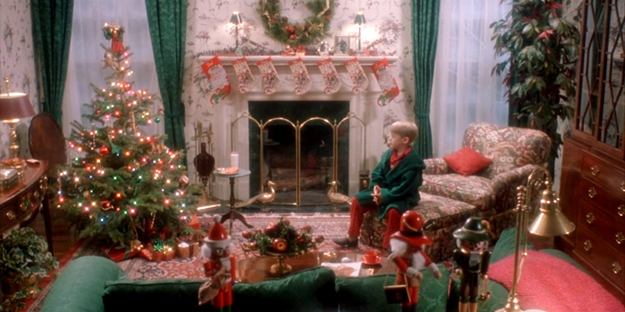 Kevin sits home alone in an empty living room. It is decorated in lavish Christmas decorations. 