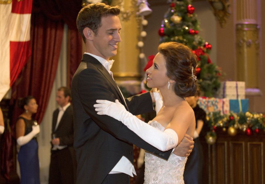 The couple dances in a ballroom that's decorated for Christmas.