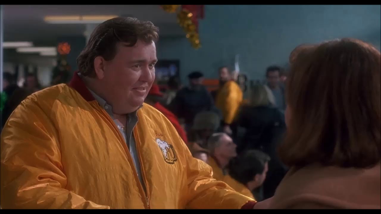 John Candy as Gus talks to Kate McCallister. He is wearing an unforgettable bright yellow jacket. 