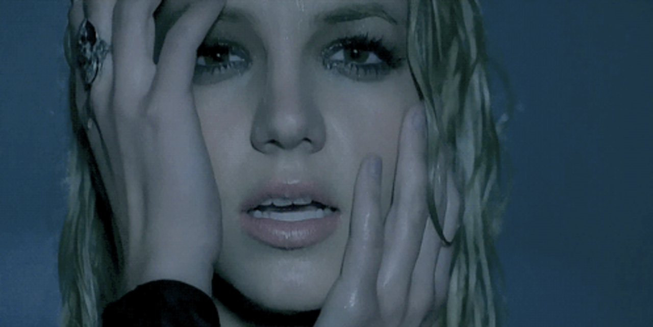 Britney Spears from the music video for one of her songs, Stronger. She's holding her hands to her face.