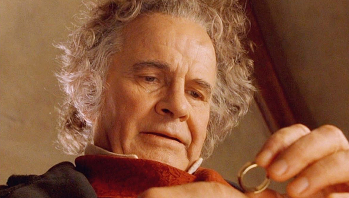 An older Bilbo Baggins (Ian Holm), stares longingly at the One Ring as he holds it between his fingers.