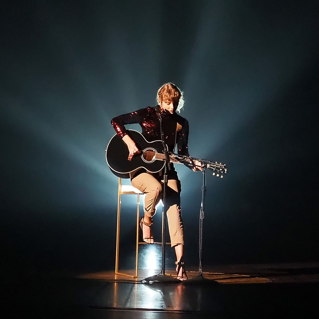 Taylor performs her song "betty" at the CMAs in a sparkly shirt, holding a guitar.