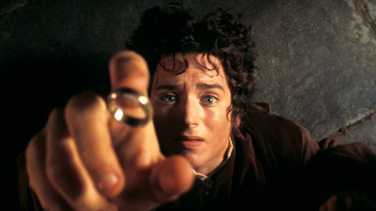 Frodo, Elijah Wood, reaches desperately for the ring with his index finger protruding.