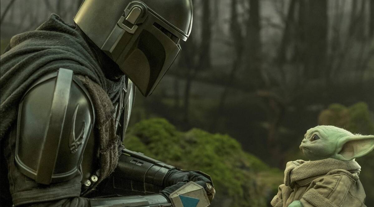 The Mandalorian talks to Grogu in a mossy forest.