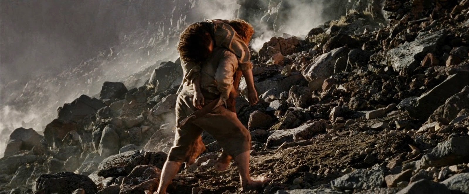 Samwise Gamgee (Sean Astin) carries Frodo Baggins (Elijah Wood) on his back up the rocky slopes of Mount Doom.