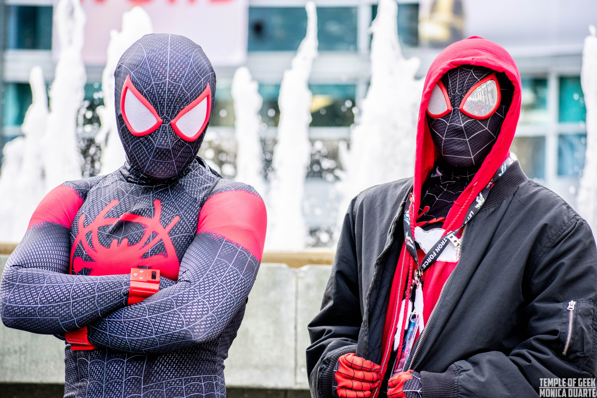 Two people dressed up as SpiderMan, Miles Morales, standing in front of 