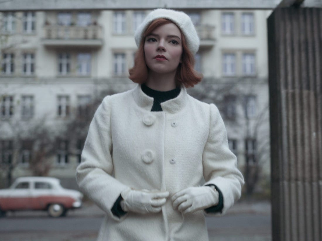 Dressed in a white jacket and white hat, Beth looks like the white queen piece in chess. She just won the world championship and left the car taking her to the airport. 