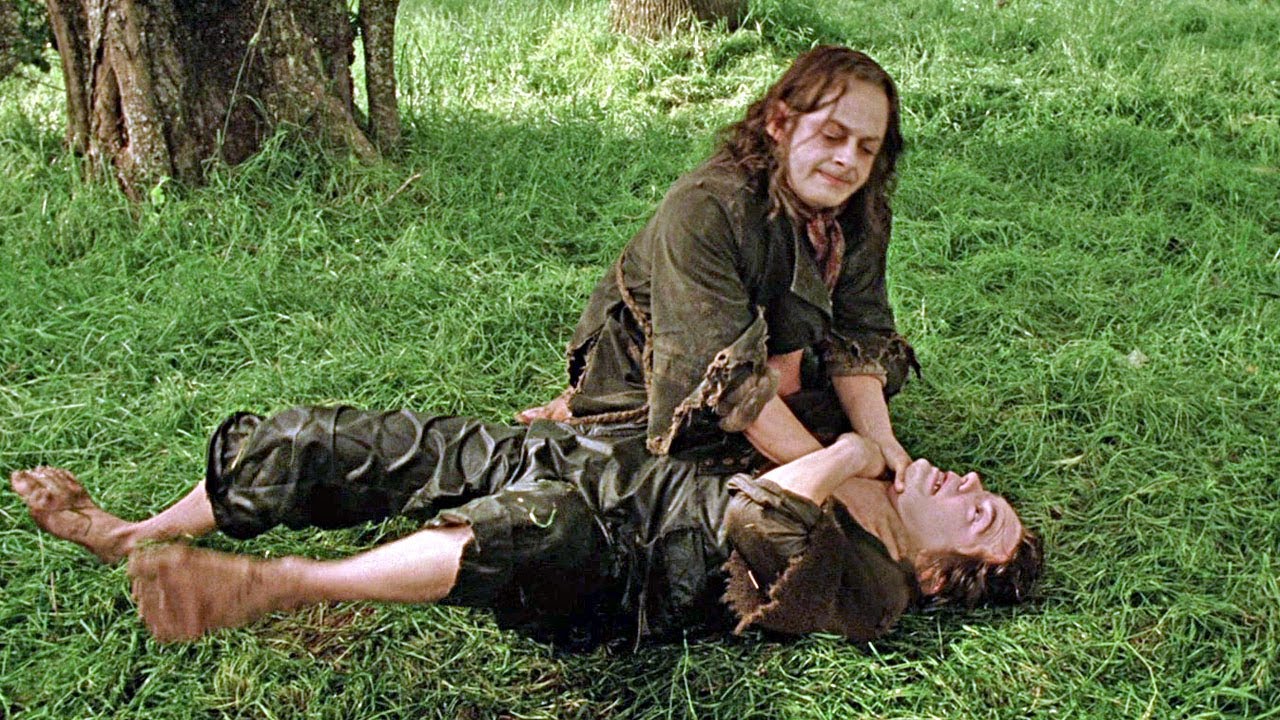 Sméagol (Andy Serkis) has Déagol (Thomas Robins) in a chokehold as they grapple in a grassy field.