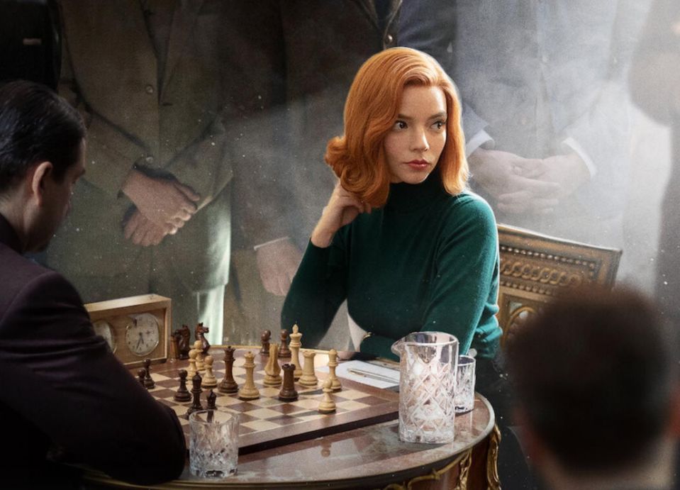 Beth Harmon from the Queen's Gambit faces opponent at a chess table.