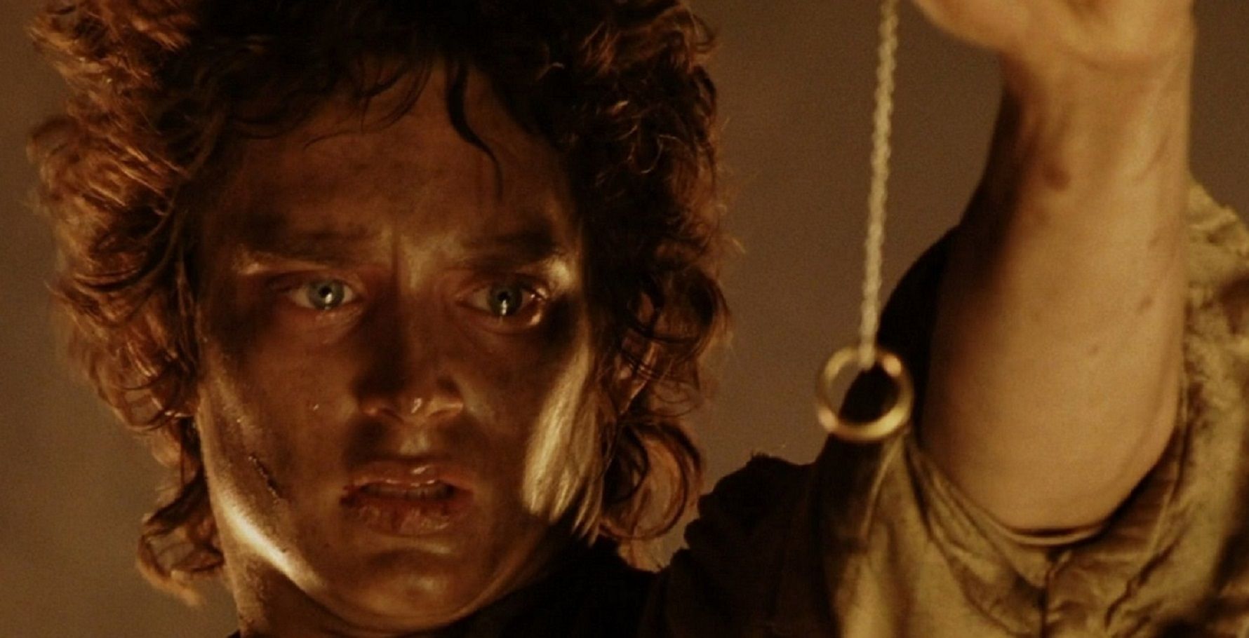 Image of Frodo holding up the ring on the cliff of the fire pit in Mount Doom. 