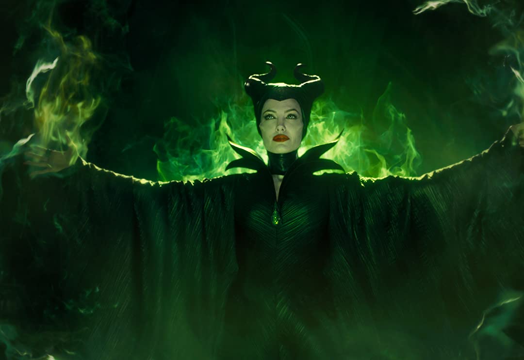 Maleficent is using her magic to create green fire with an evil smirk on her face.