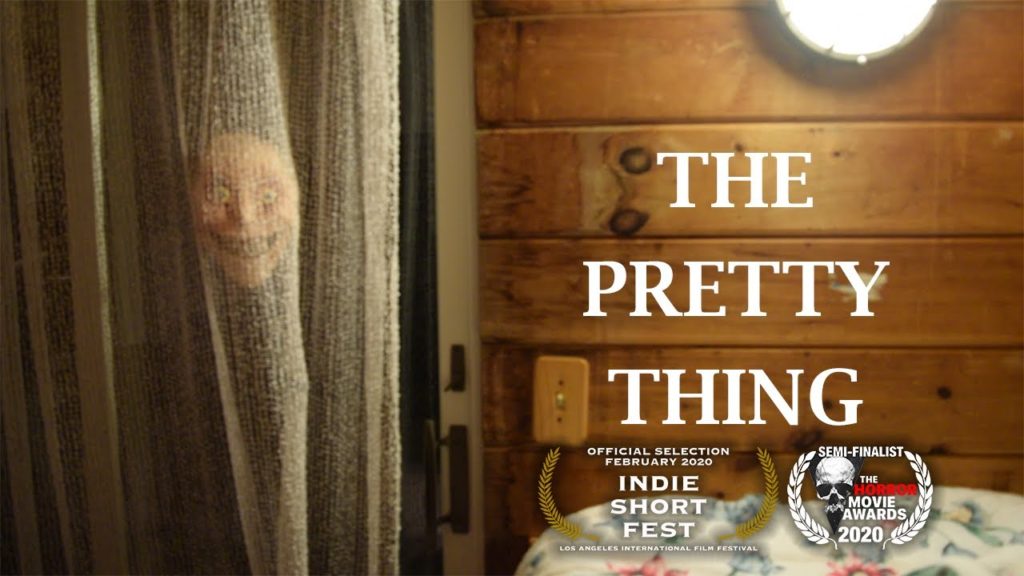 The pretty thing peers into the window in the cover shot from the Youtube Horror Short "The Pretty Thing," uploaded by Dylan Clark. 