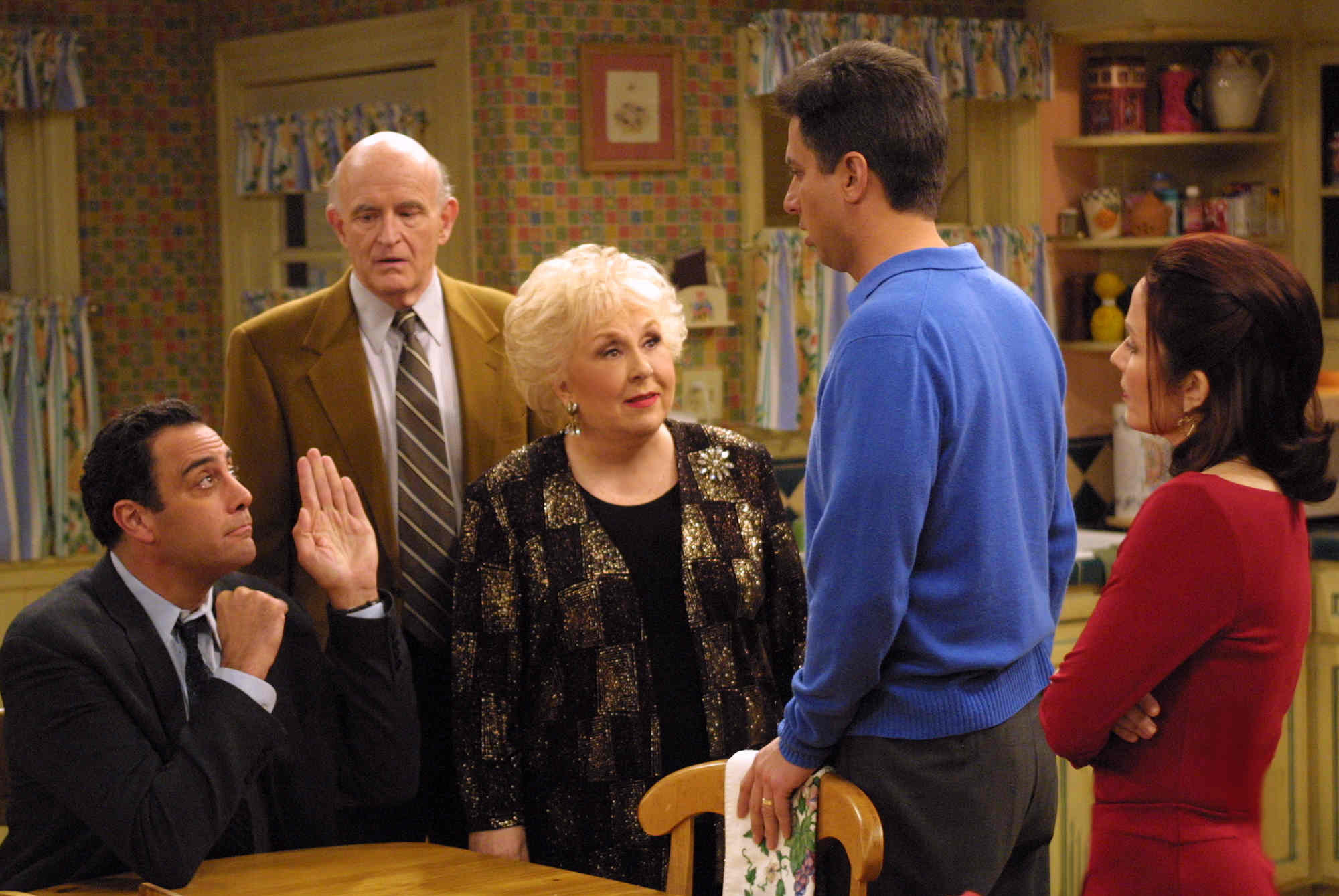 Marie, Debra, Raymond, Robert, and Frank Barone are huddled around a table, having one of their typical family altercations.