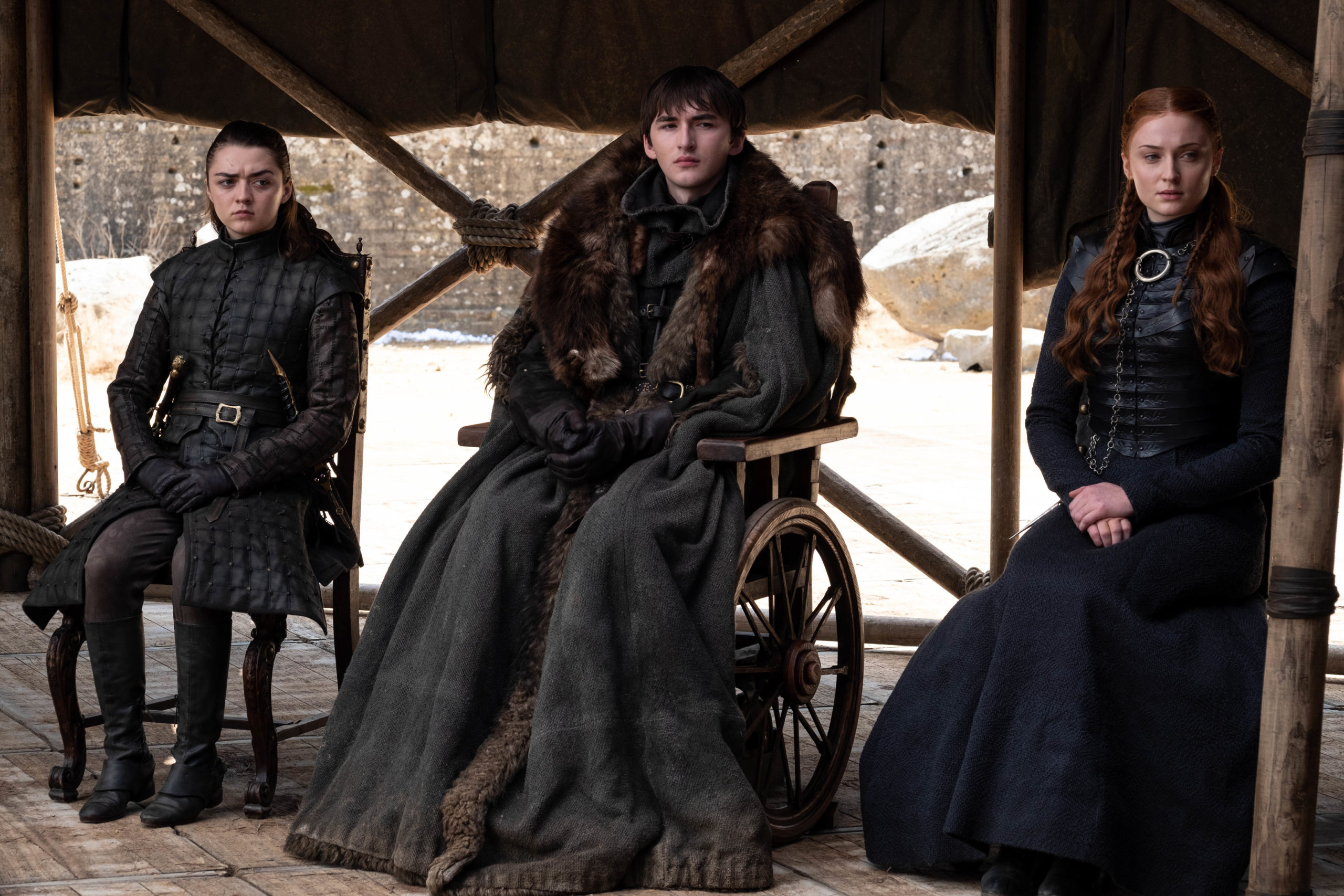 Arya (left), Bran, and Sansa (right) sit in a row at the meeting to decide who will rule the Seven Kingdoms at the end of Game of Thrones.