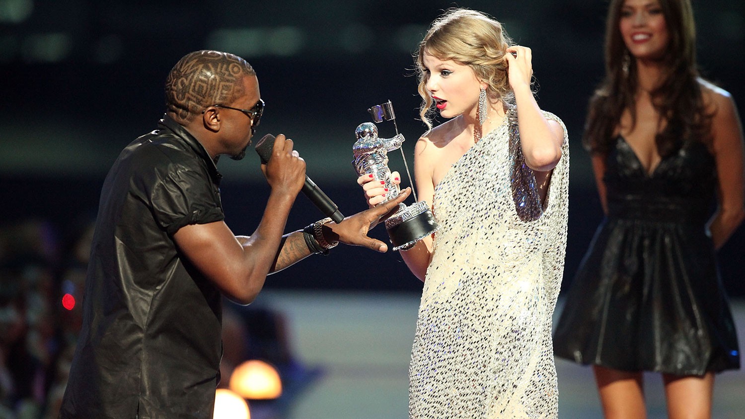 Taylor Swift at the 2009 VMAs. Kanye West is taking her microphone.