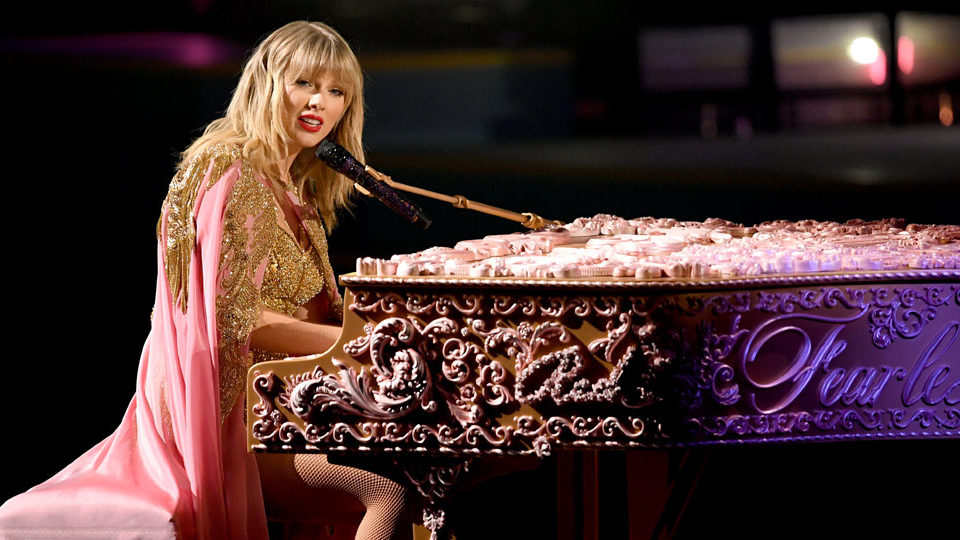 Taylor Swift during her 2019 ama performance. She is sitting at a piano performing her song, Lover.