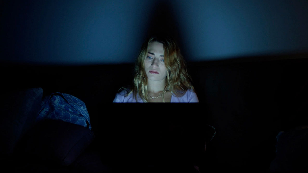 Mia looking at her computer in a dark room