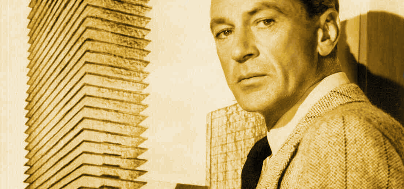 Gary Cooper as Howard Roark casts a severe look over his shoulder. A skyscraper looms in the background. 