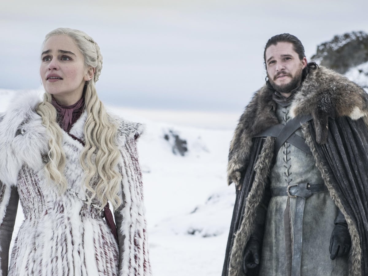 Daenerys Targeryan and Jon Snow stand together in the snow, looking up at something offscreen. 