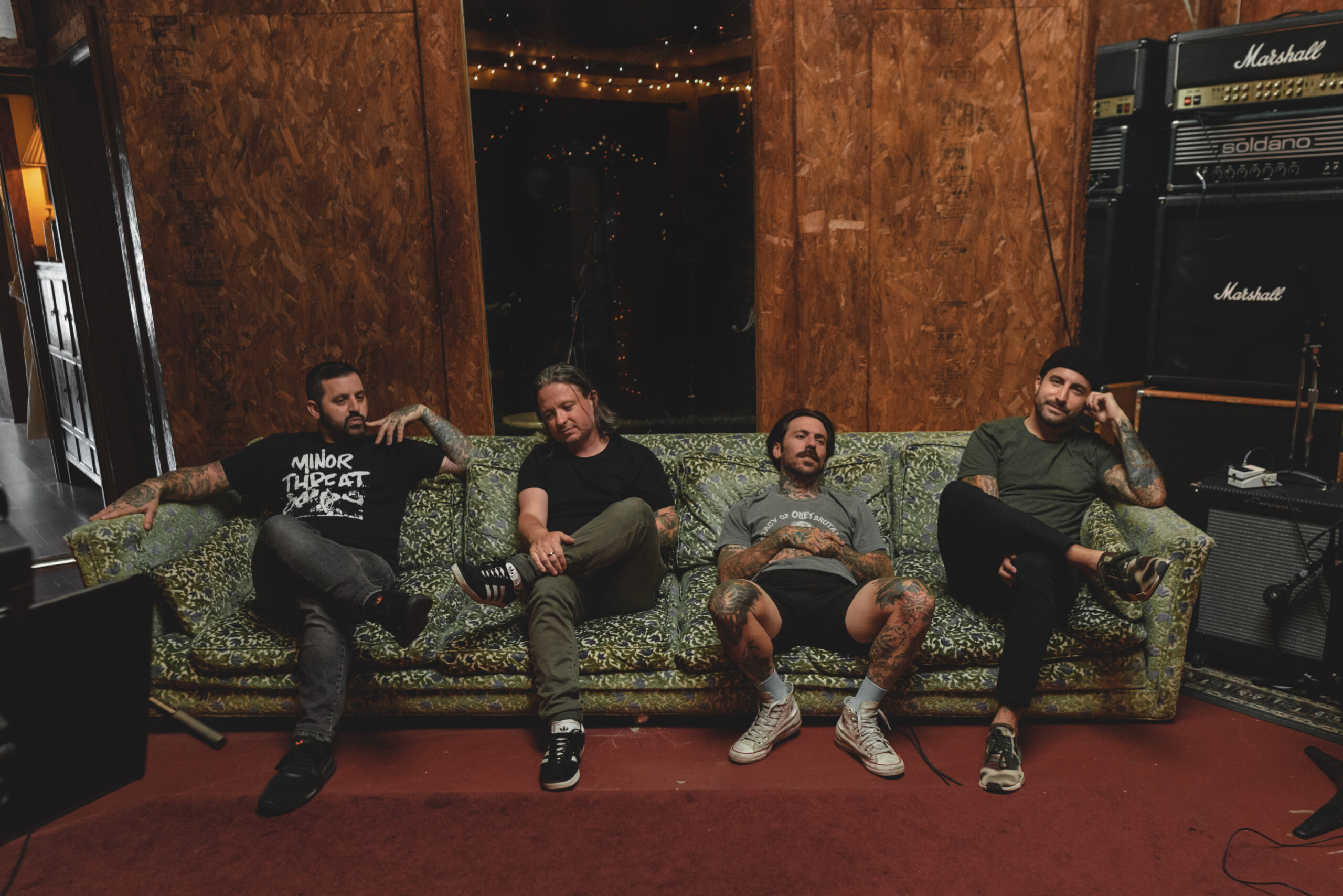 The members of Bayside pose on a saggy and well-used couch (“Vacancy.” Bayside. 2016. Hopeless Records.).