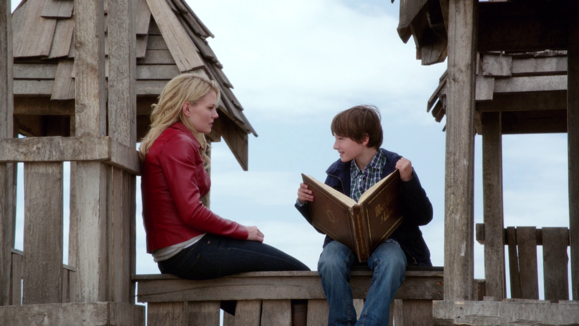 Emma and Henry sit on a play structure while they discuss some of the fairytales in Henry's book, "Once Upon a Time."