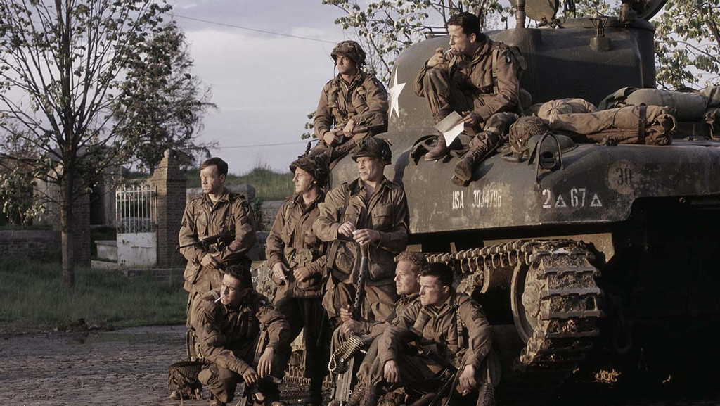 The soldiers portrayed in Band of Brothers wait ready for battle near a tank. (Photo by HBO).
