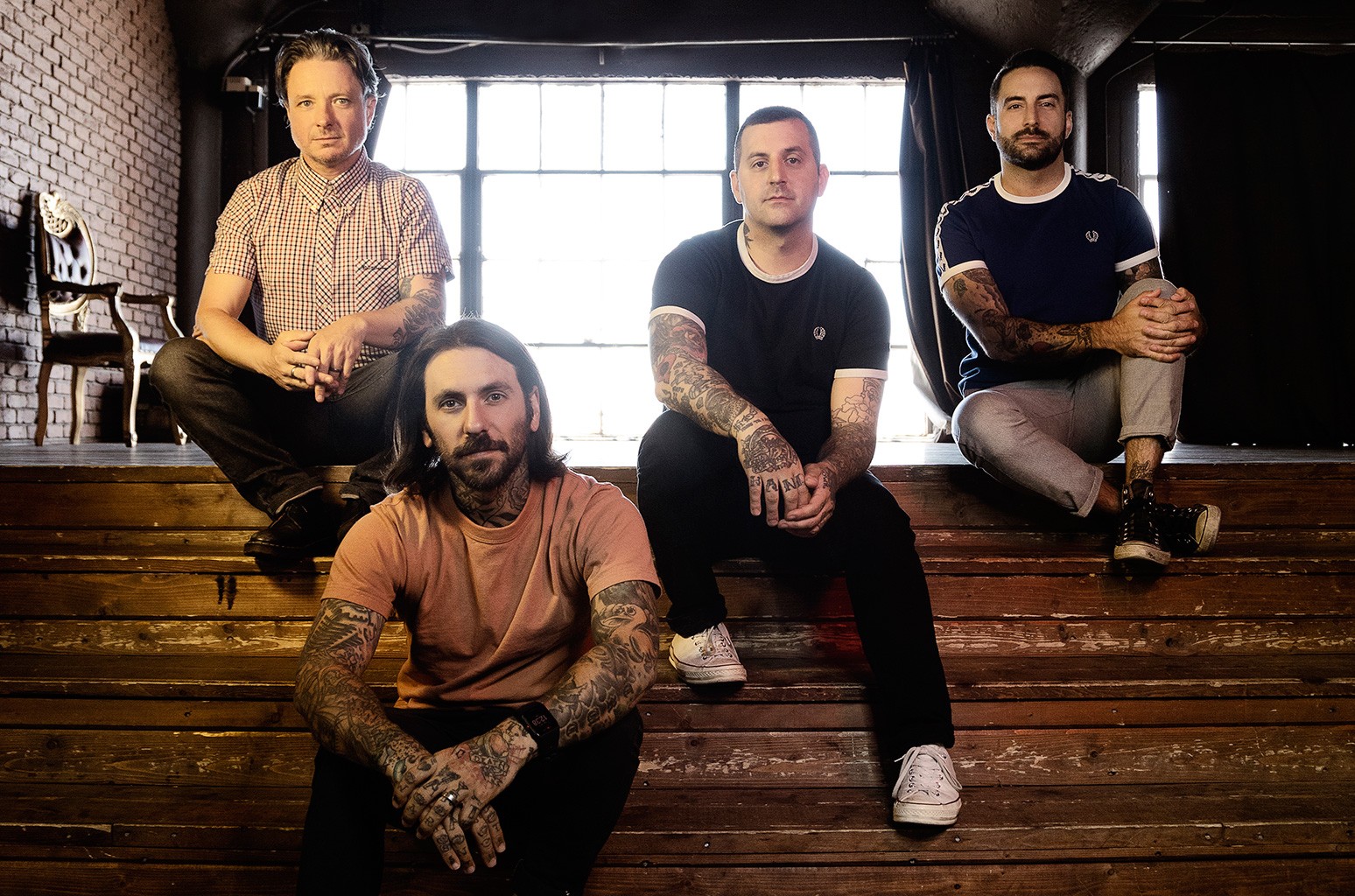 The members of Bayside sit on wooden steps in front of a sunny window (“Vacancy.” Bayside. 2016. Hopeless Records.).